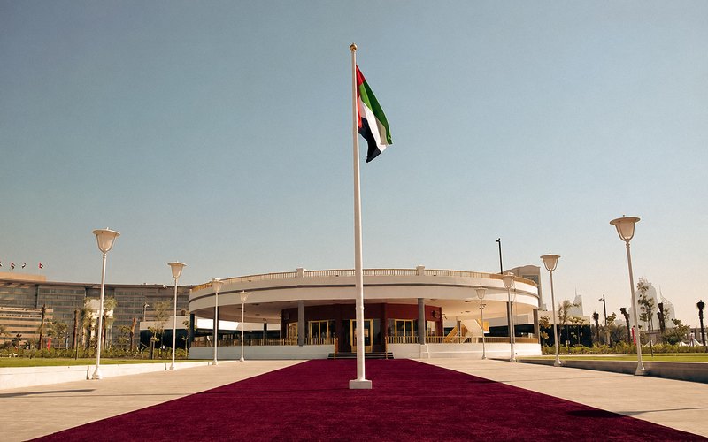 Union House in Dubai: a white circular colonnaded building fronted by a flagpole flying the UAE flag and a red carpet leading to its entrance